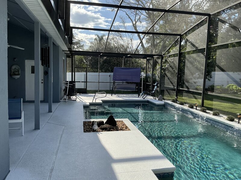 Finished screen enclosure over a pool and spa, with clear views through new mesh to the yard beyond